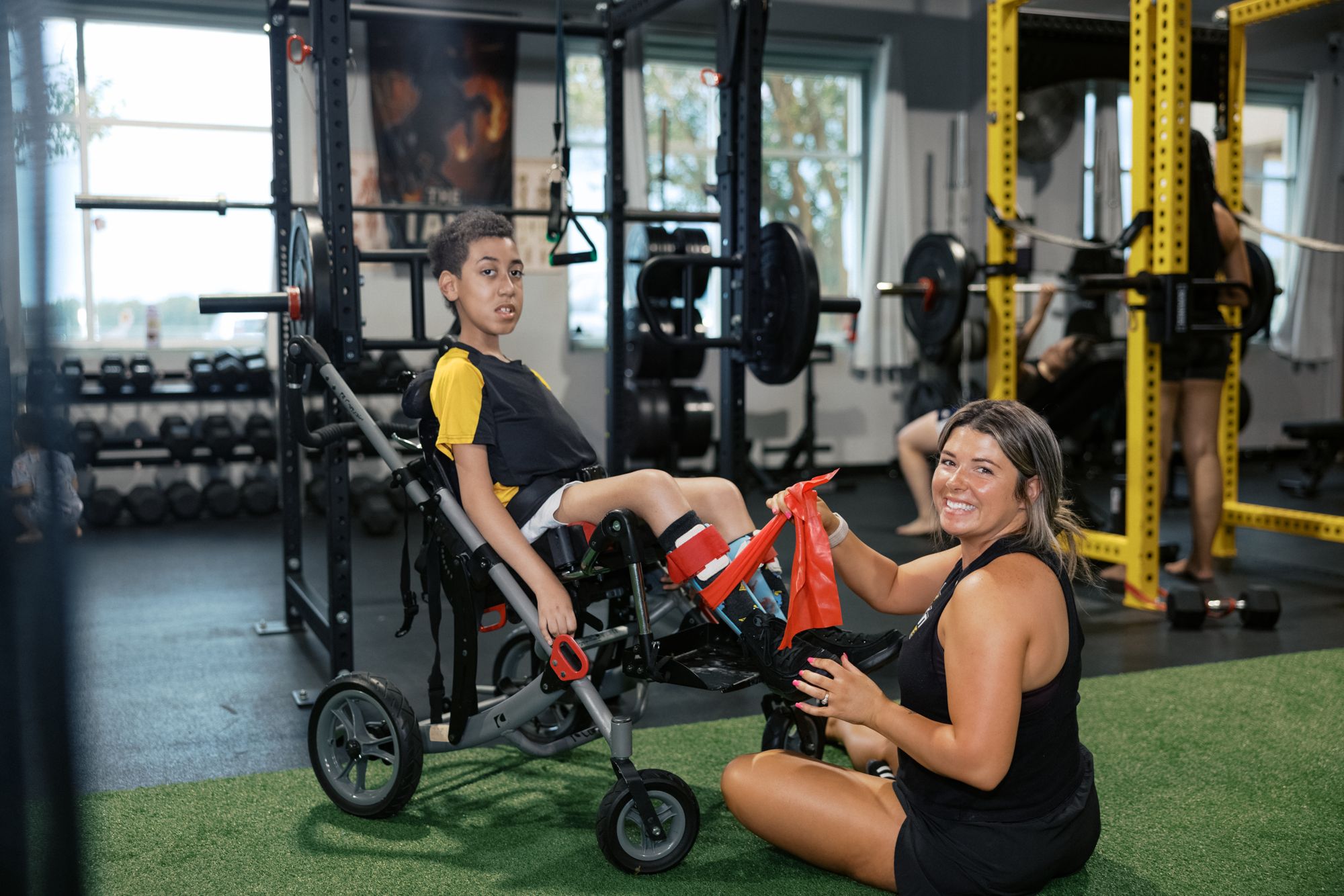 A coach on the floor beside her athlete's chair, working a band drill